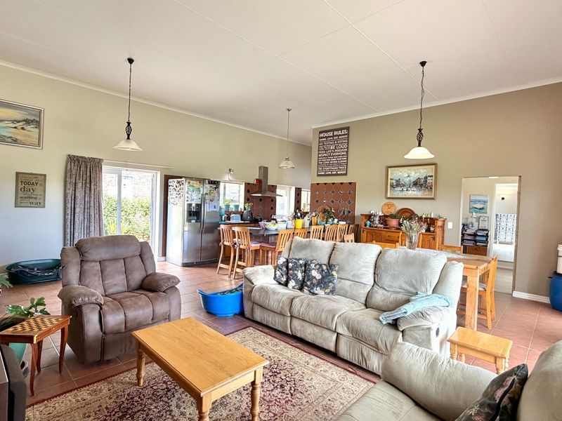 Spacious open-plan living and kitchen area featuring tiled flooring, pendant lighting, and a functional kitchen island with built-in cabinetry.