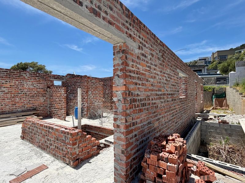 A construction site view showing the exposed brick walls and concrete foundation of a property currently under development.