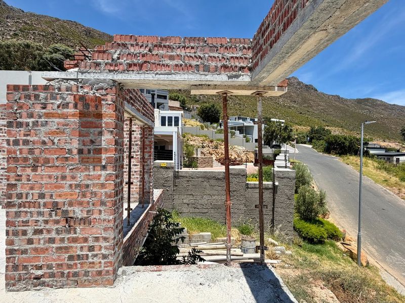 A construction site view showing exposed brickwork, concrete lintels, and steel support props during the building process of a residential property.