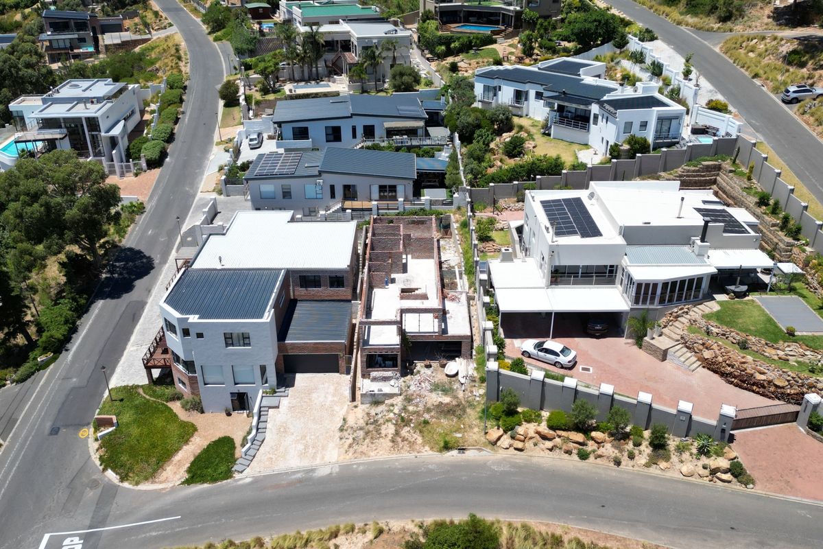 Aerial view of a residential street showing multiple properties, including a home currently under construction with exposed brickwork.