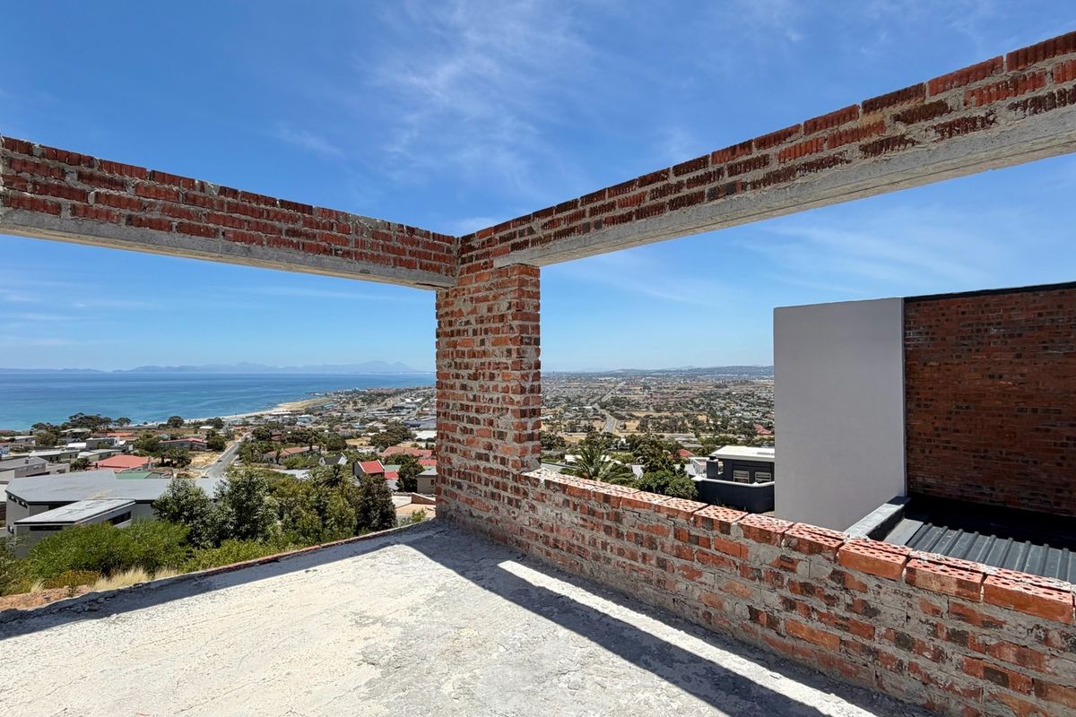 An unfinished construction site showing exposed brickwork and concrete structure with panoramic coastal and urban views.