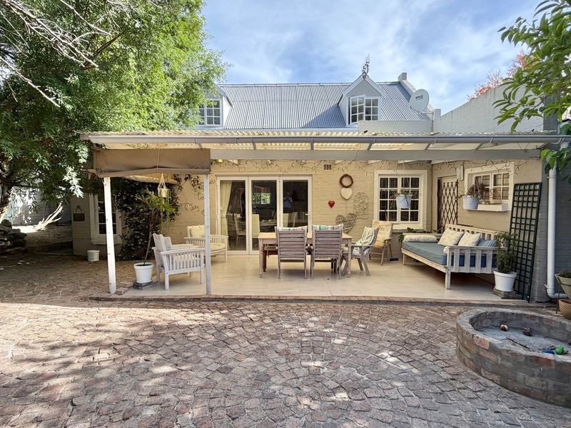 Rear view of the property featuring a covered patio area, tiled flooring, and a brick-paved courtyard with a built-in fire pit.