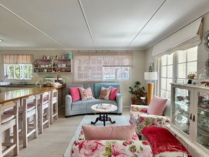 Open-plan living area featuring a functional kitchen with breakfast bar, integrated appliances, and direct access to the outdoors through glass doors.