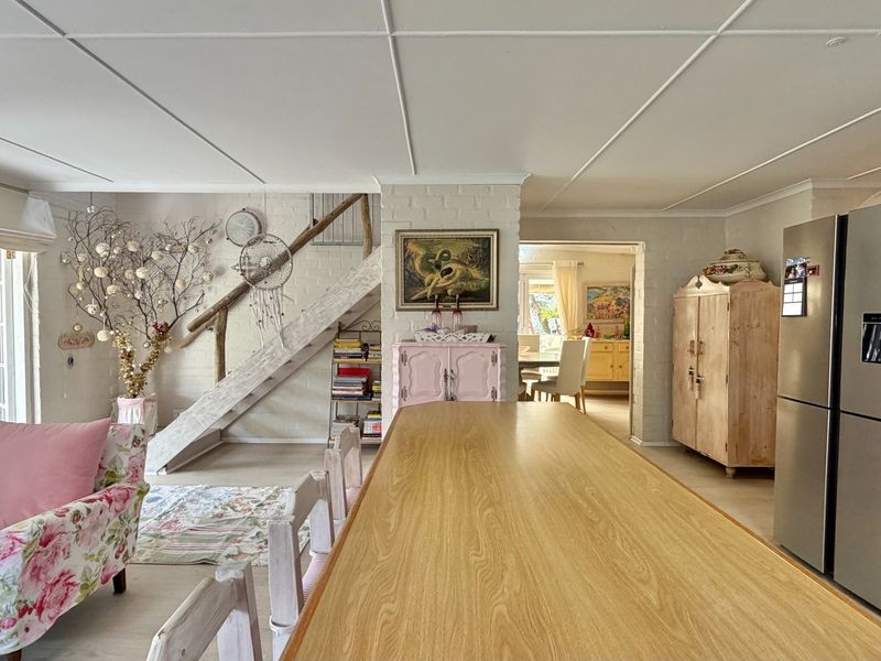 Open-plan living area featuring painted brick walls, a central staircase, and a tiled ceiling, connecting to adjacent dining and kitchen spaces.