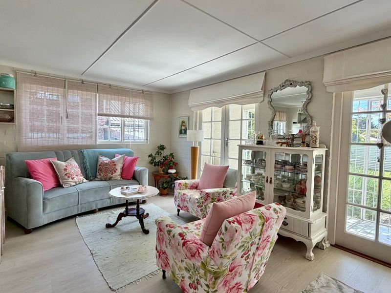 A bright and inviting living room featuring laminate flooring, built-in shelving, and double french doors providing direct access to the outdoor area.