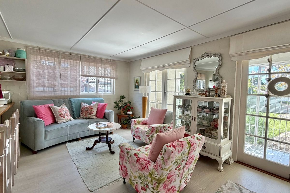 A bright and inviting living room featuring laminate flooring, built-in shelving, and double french doors providing direct access to the outdoor area.