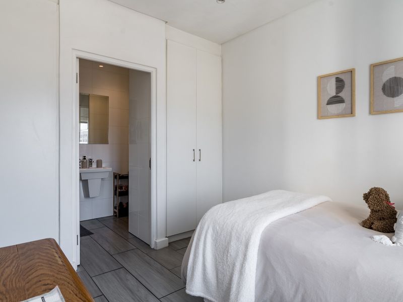 A bright bedroom featuring built-in cupboards, tiled flooring, and direct access to an en-suite bathroom.