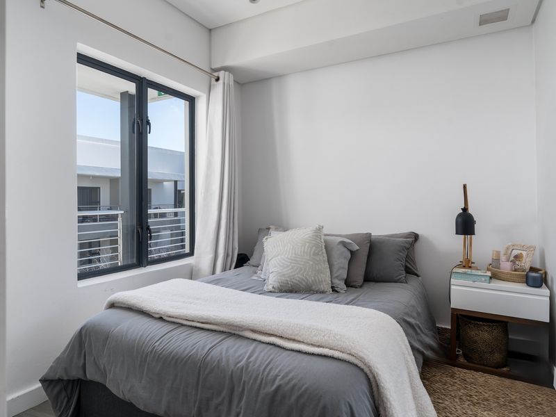 A bright and modern bedroom featuring neutral walls, clean lines, and a large window allowing for natural light.