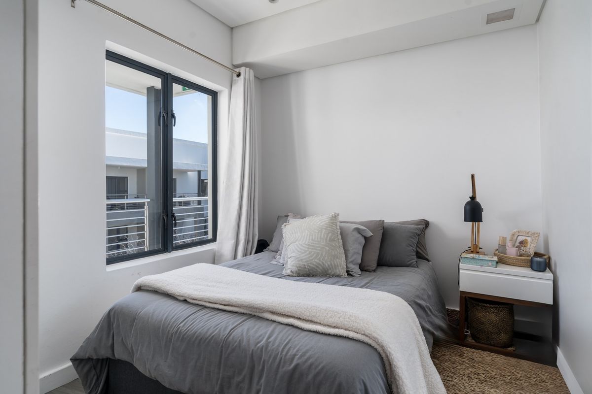 A bright and modern bedroom featuring neutral walls, clean lines, and a large window allowing for natural light.