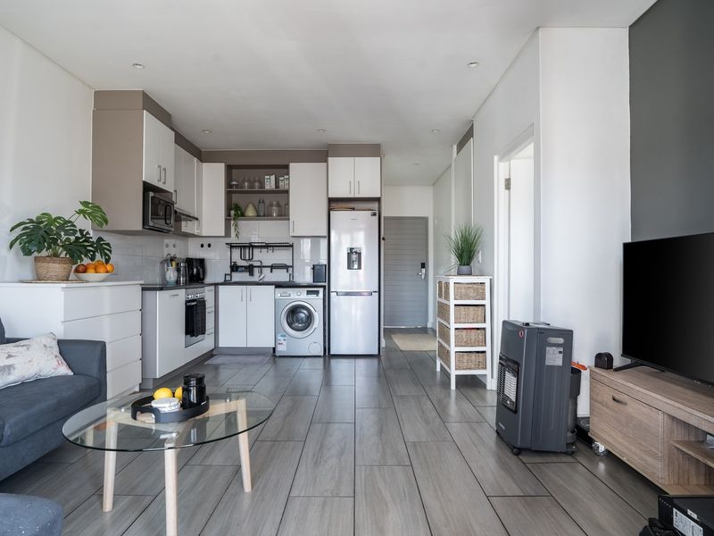 Modern open-plan living area featuring a well-appointed kitchen with built-in cabinetry, integrated appliances, and sleek tiled flooring throughout.