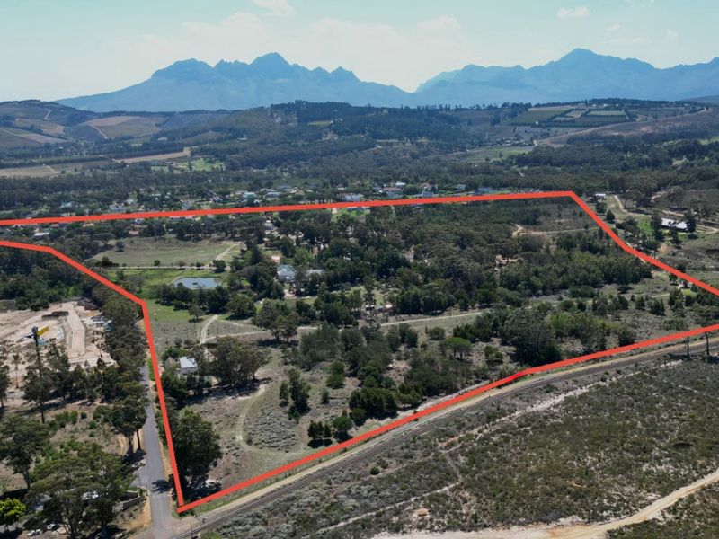 An aerial view of a large, expansive residential land parcel featuring mature trees, natural vegetation, and scenic mountain views in the background.