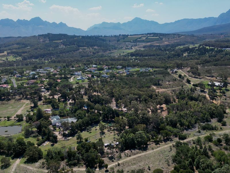 An expansive aerial view of a rural residential area nestled against a scenic mountain range, showcasing the surrounding landscape and natural terrain.