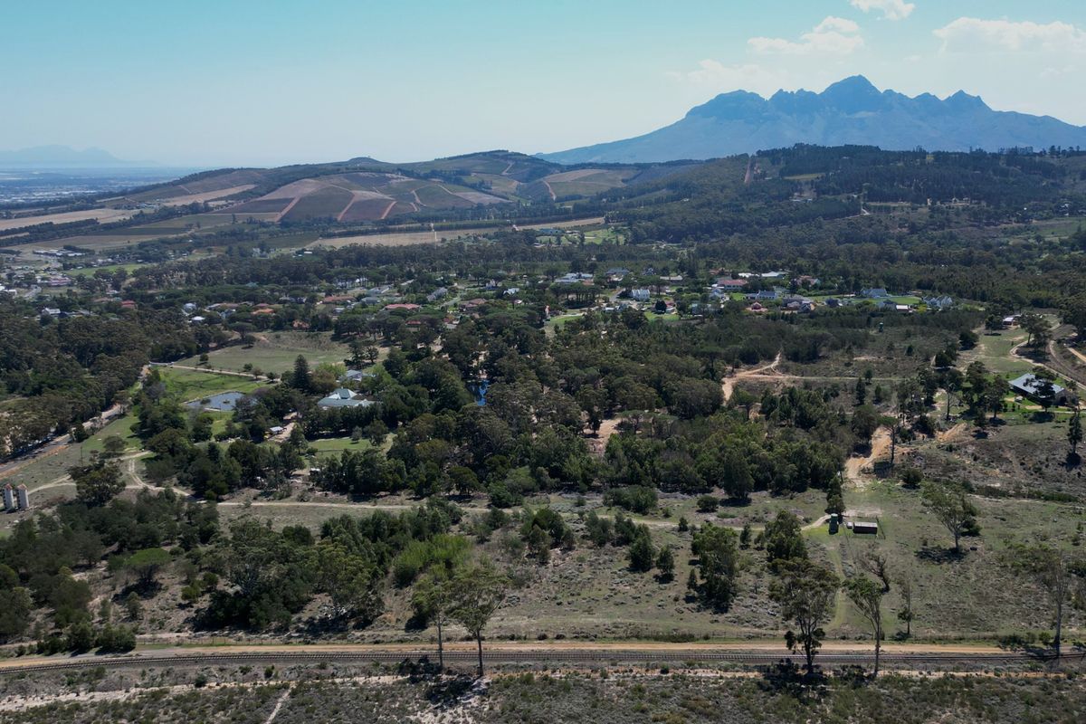 An expansive aerial view of the residential land, showcasing the surrounding natural landscape, mature trees, and distant mountain range.