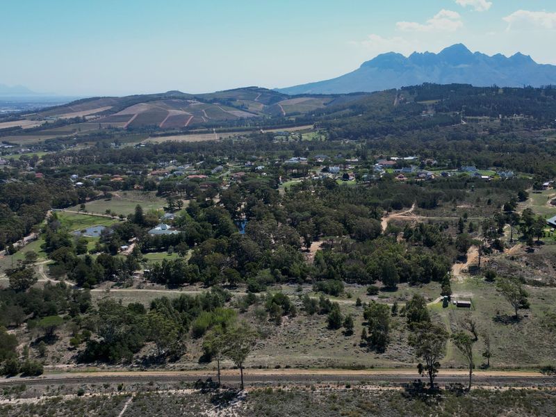An expansive aerial view of the residential land, showcasing the surrounding natural landscape, mature trees, and distant mountain range.