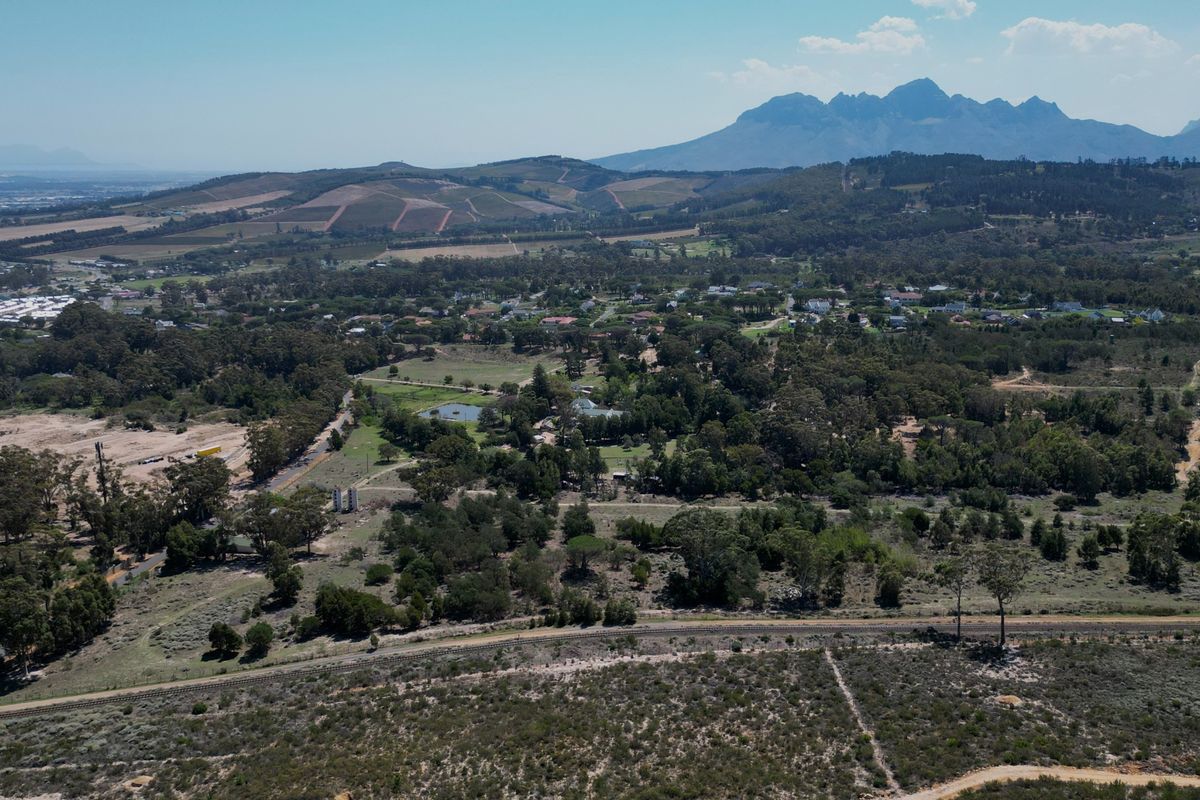 An expansive aerial view of the residential land, showcasing the surrounding natural landscape, mature trees, and distant mountain range.