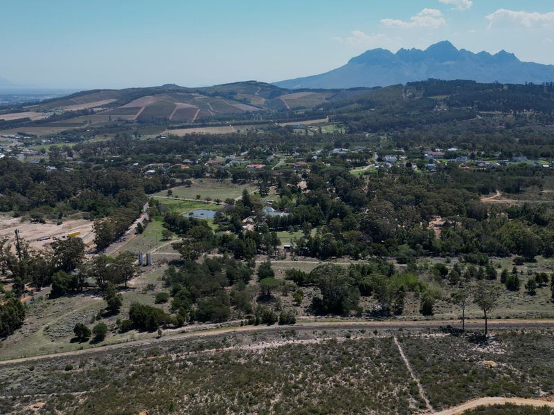 An expansive aerial view of the residential land, showcasing the surrounding natural landscape, mature trees, and distant mountain range.