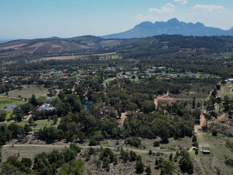 An expansive aerial view of the residential landscape, showcasing the surrounding natural terrain, mature trees, and distant mountain range.