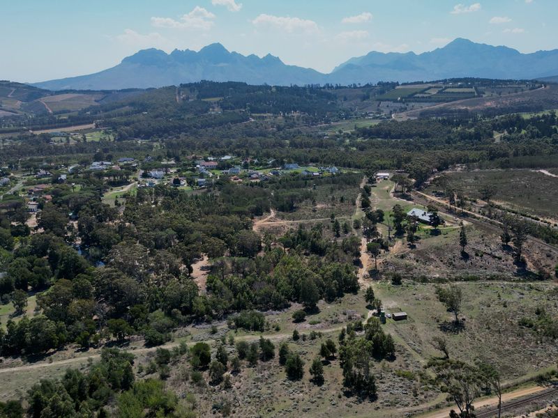 An expansive aerial view of the residential land, showcasing the surrounding natural landscape, mature trees, and scenic mountain backdrop.