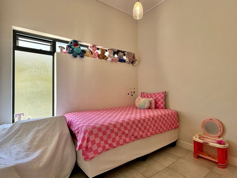 A compact bedroom featuring tiled flooring and a high-level window, providing natural light and a functional layout.
