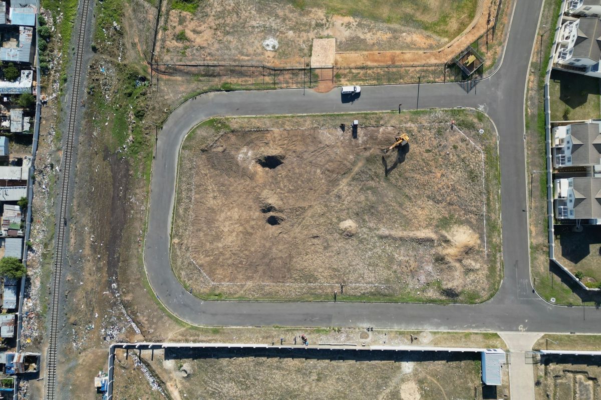 Aerial view of a vacant plot of land surrounded by paved roads and residential development.