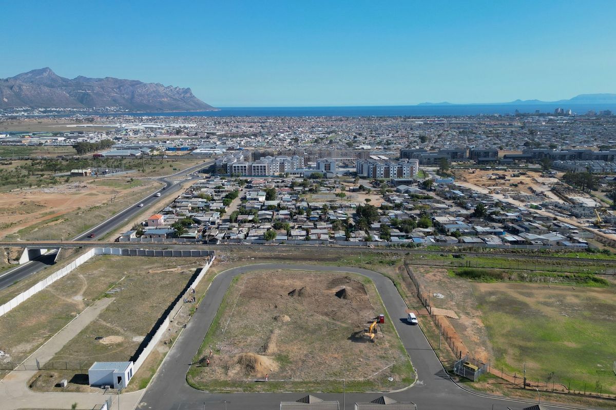 An aerial view of the surrounding neighborhood and landscape, showcasing the property's location, access roads, and proximity to local infrastructure and coastal views.
