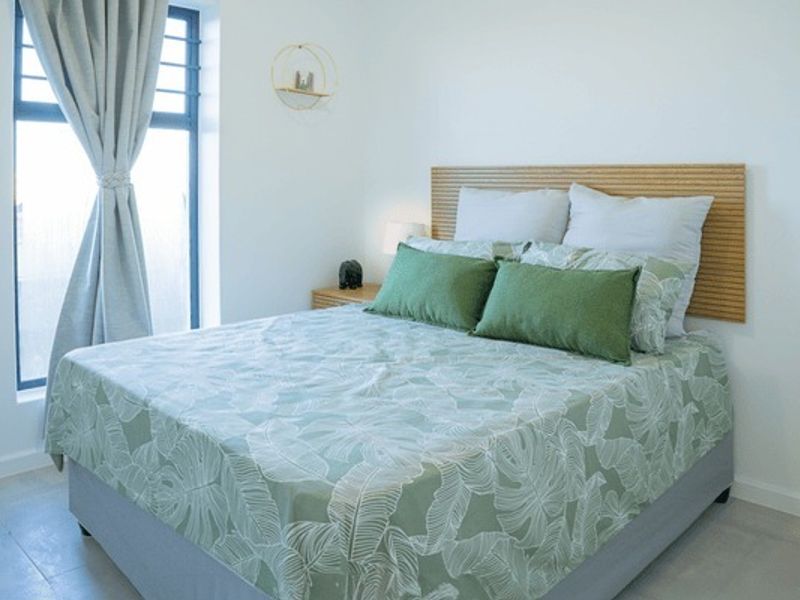 A bright and modern bedroom featuring large windows, neutral wall finishes, and tiled flooring, creating a clean and comfortable living space.