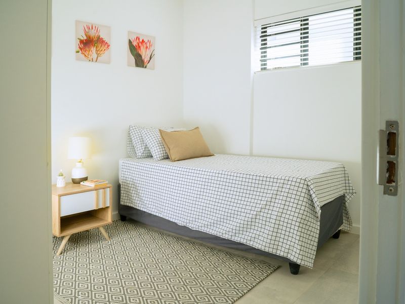 A compact bedroom featuring tiled flooring and venetian blinds, offering a clean and functional space.