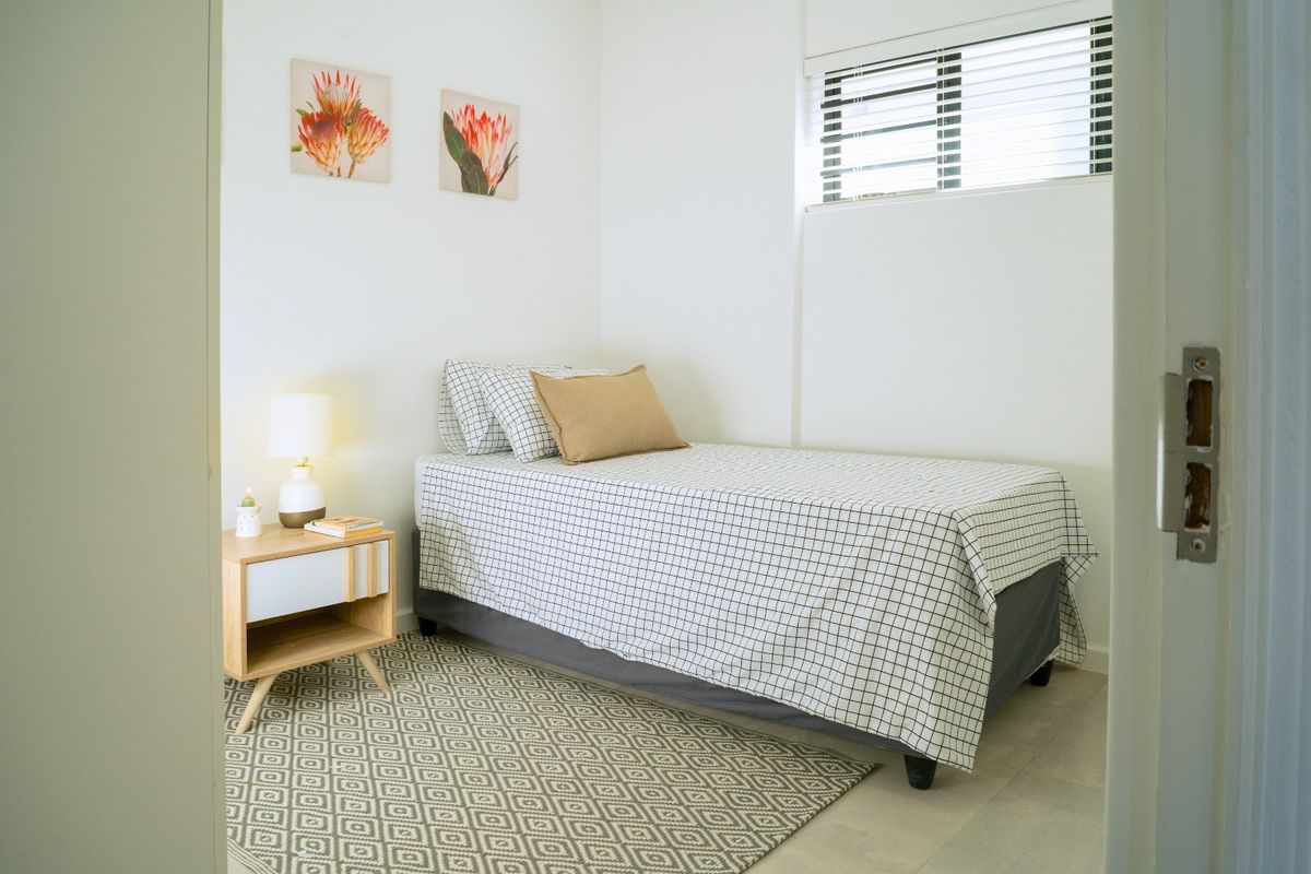 A compact bedroom featuring tiled flooring and venetian blinds, offering a clean and functional space.