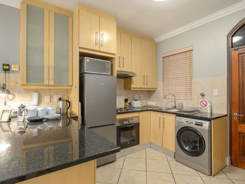 A functional kitchen featuring light wood cabinetry, granite countertops, built-in appliances, and tiled flooring, offering a practical and well-maintained workspace.