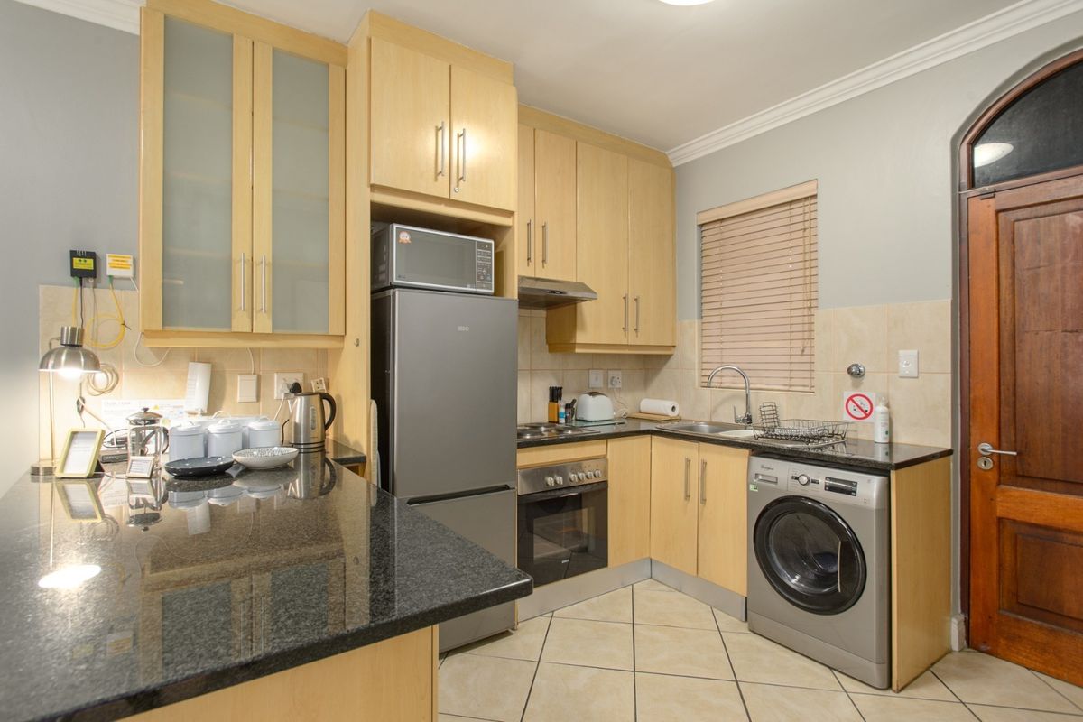A functional kitchen featuring light wood cabinetry, granite countertops, built-in appliances, and tiled flooring, offering a practical and well-maintained workspace.