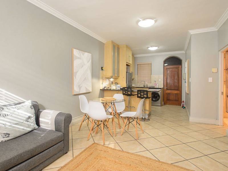 Open-plan living and kitchen area featuring tiled flooring, built-in cabinetry, and a classic arched wooden entrance door.