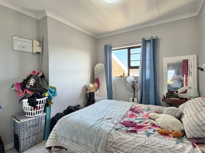 A standard bedroom featuring a built-in cupboard, coving, and a window, providing a functional living space.
