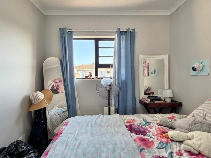 A standard bedroom featuring neutral wall finishes, a window with aluminium frames, and decorative cove cornicing.