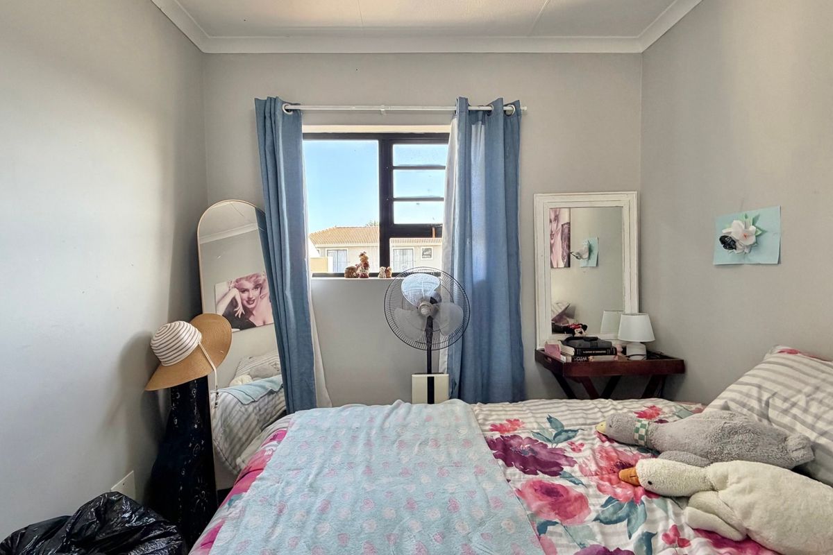 A standard bedroom featuring neutral wall finishes, a window with aluminium frames, and decorative cove cornicing.
