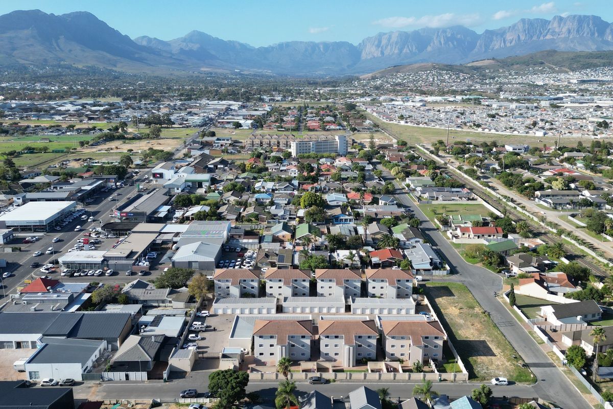 An aerial view of the apartment complex and surrounding residential and commercial neighborhood with mountain views in the distance.