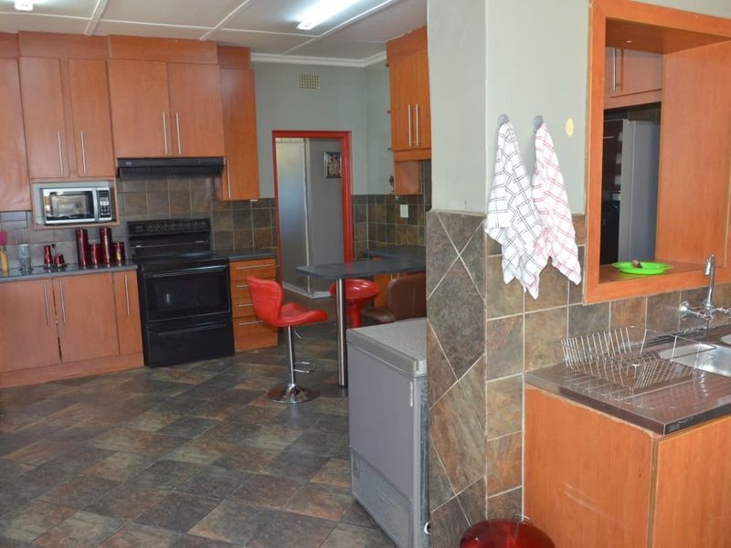Functional kitchen featuring wood-tone cabinetry, dark tiled flooring, a built-in microwave, and a double basin sink with a breakfast bar area.