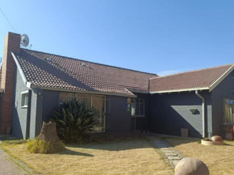 Front elevation of a single-story brick house featuring a tiled roof, prominent chimney, and a paved walkway leading to the entrance.