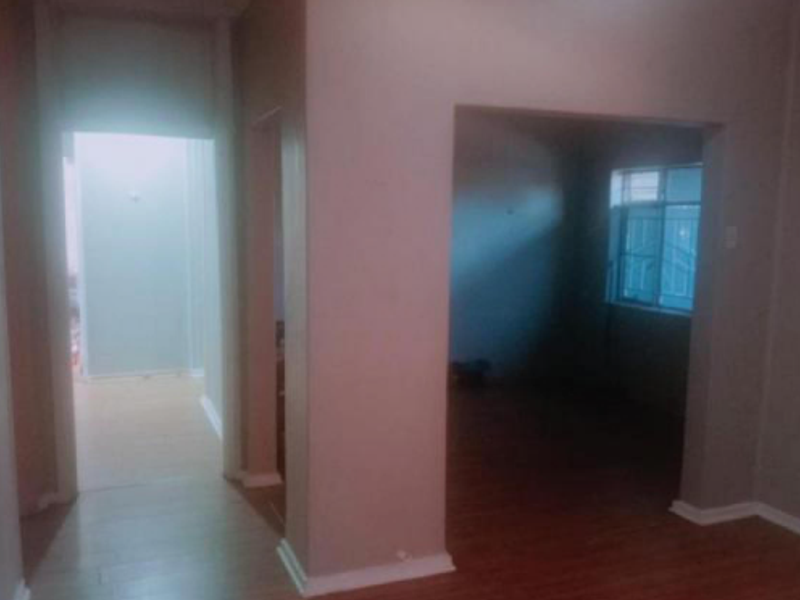 A view of an empty hallway connecting to adjacent rooms, featuring laminate flooring and neutral wall finishes.