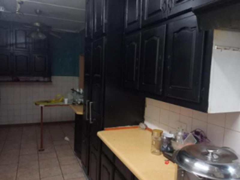 A dated kitchen featuring dark built-in cabinetry, tiled backsplash, and laminate countertops, offering significant potential for a modern renovation.
