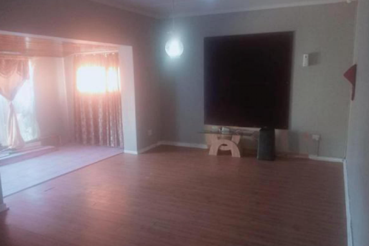 Spacious living area featuring laminate flooring and neutral wall tones, offering a versatile layout for comfortable family living.