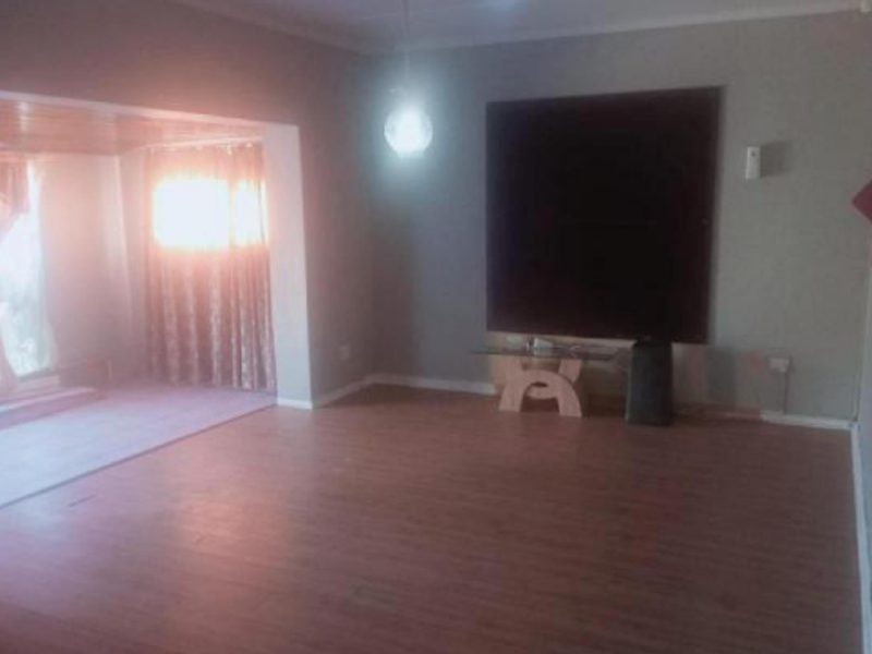 Spacious living area featuring laminate flooring and neutral wall tones, offering a versatile layout for comfortable family living.
