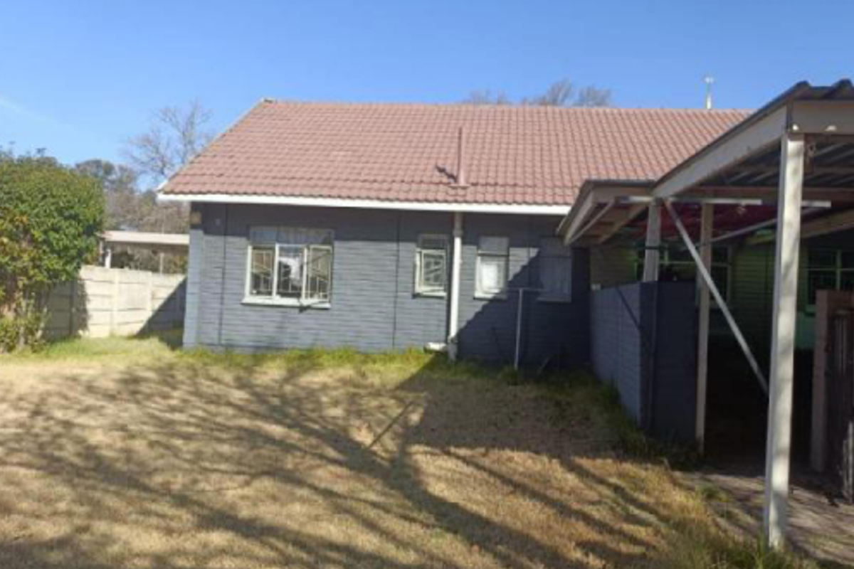 Rear view of the property featuring a tiled roof, brick facade, and a covered patio area overlooking the garden.