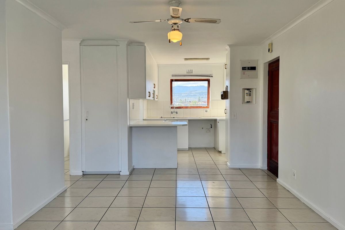 A functional, empty kitchen area featuring tiled flooring, built-in cabinetry, and a ceiling fan, offering a clean canvas for potential updates.