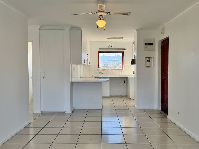 A functional, empty kitchen area featuring tiled flooring, built-in cabinetry, and a ceiling fan, offering a clean canvas for potential updates.