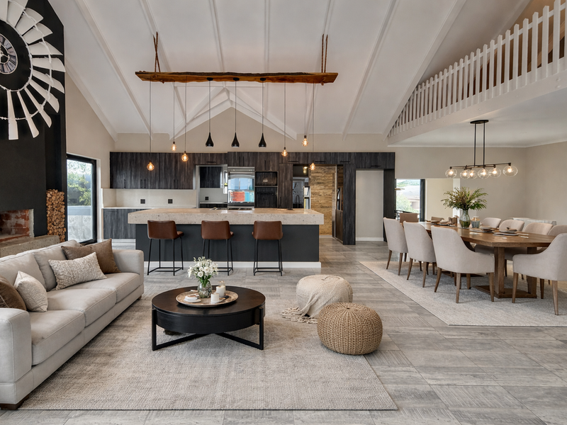 Spacious open-plan living, dining, and kitchen area featuring a vaulted ceiling, modern kitchen island, fireplace, and a mezzanine level overlooking the main space.