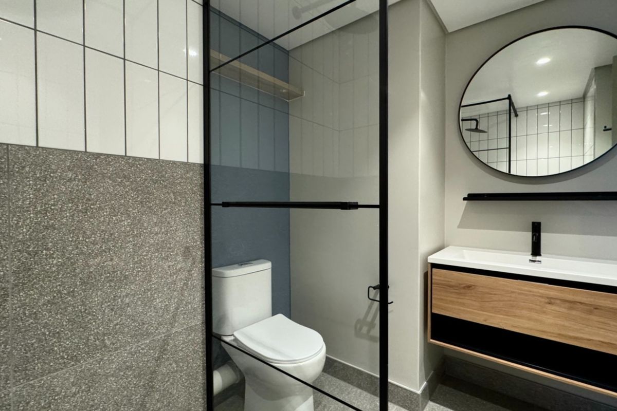 Modern bathroom featuring a wall-mounted vanity with integrated basin, black fixtures, a glass shower screen, and contemporary tiled finishes.
