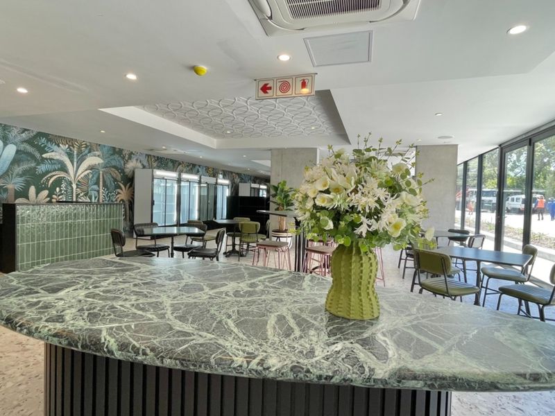 Modern open-plan communal area featuring a marble-topped bar, decorative wallpaper, tiled flooring, and large glass sliding doors providing ample natural light.