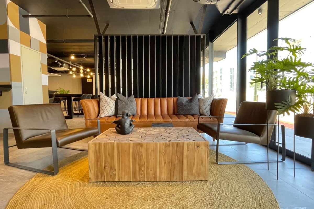 Modern open-plan living area featuring tiled floors, exposed industrial-style ceiling, and large floor-to-ceiling windows providing ample natural light.