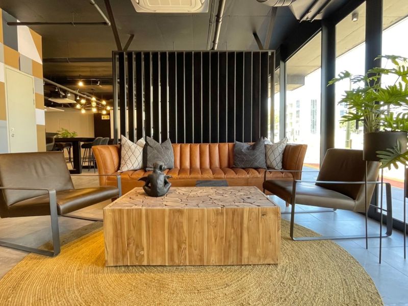 Modern open-plan living area featuring tiled floors, exposed industrial-style ceiling, and large floor-to-ceiling windows providing ample natural light.