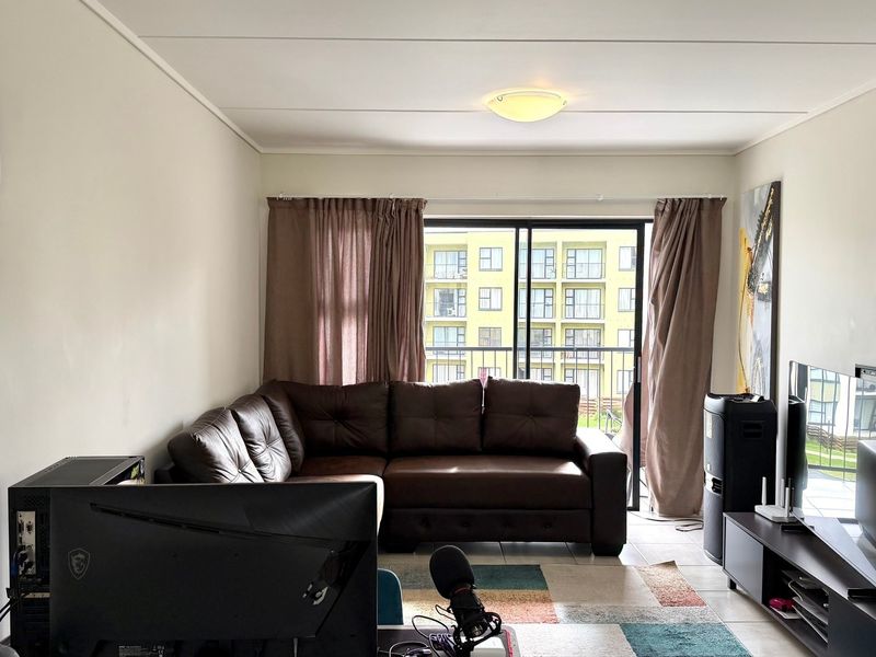 A functional living room featuring tiled flooring and a large sliding glass door that provides access to an outdoor balcony area.